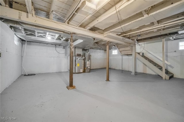 basement featuring stairs, gas water heater, and heating unit