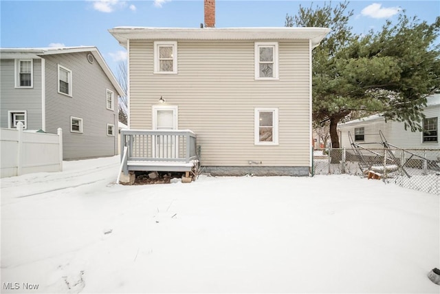 snow covered property featuring fence and a chimney