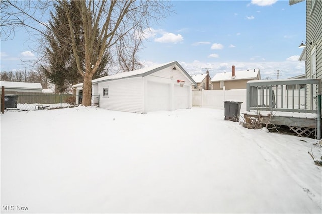 snowy yard featuring an outdoor structure, fence, and a detached garage