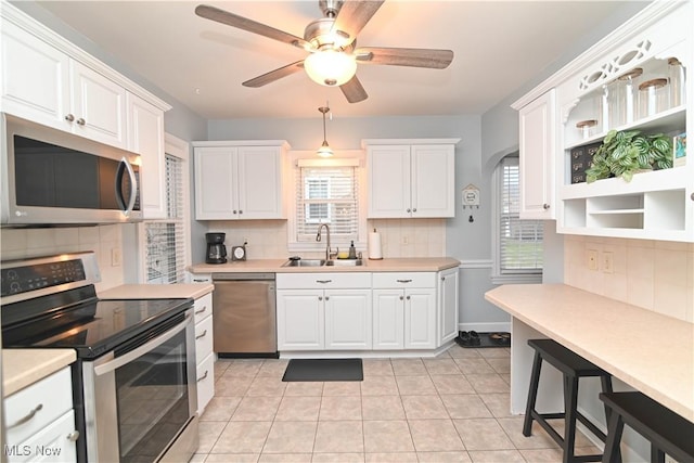 kitchen featuring sink, white cabinetry, light tile patterned floors, appliances with stainless steel finishes, and ceiling fan