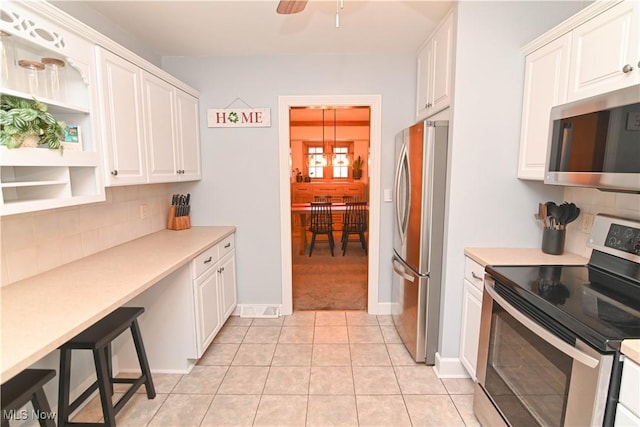 kitchen featuring hanging light fixtures, light tile patterned flooring, white cabinets, and appliances with stainless steel finishes