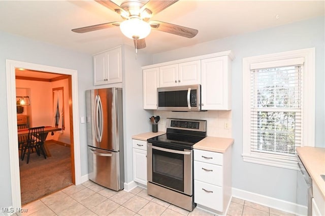 kitchen featuring white cabinetry, ceiling fan, stainless steel appliances, and light tile patterned floors