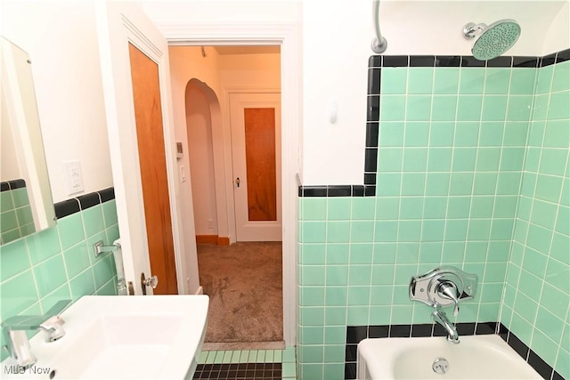 bathroom with bathing tub / shower combination, sink, and tile walls