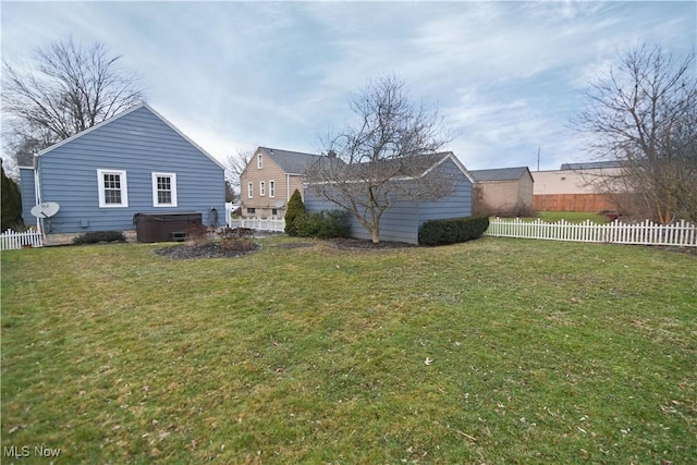 back of property with a hot tub and a yard