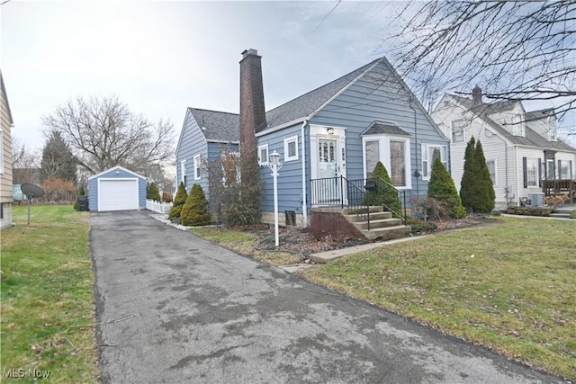 bungalow featuring a garage, an outbuilding, and a front lawn