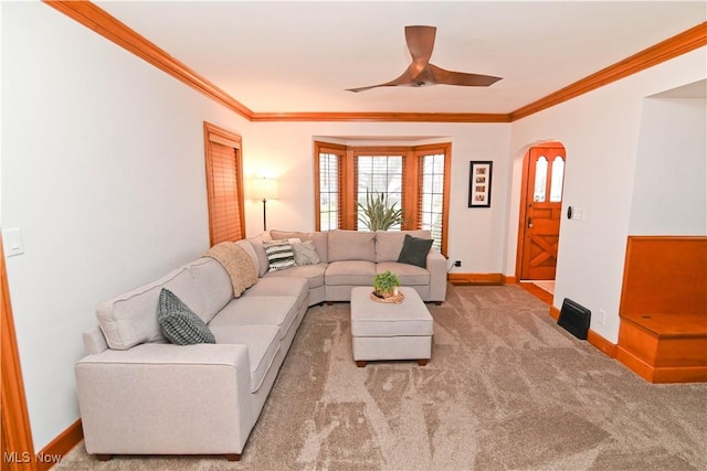 carpeted living room with crown molding and ceiling fan