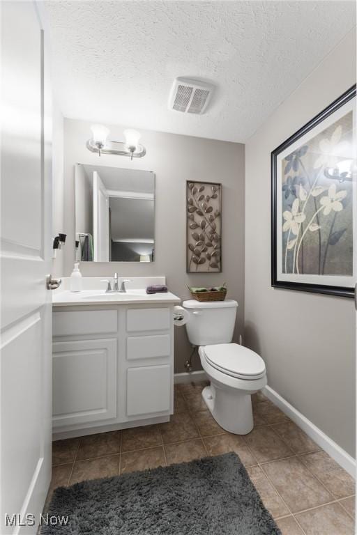 bathroom with vanity, toilet, tile patterned flooring, and a textured ceiling