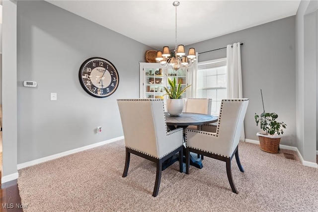 dining room featuring carpet and an inviting chandelier