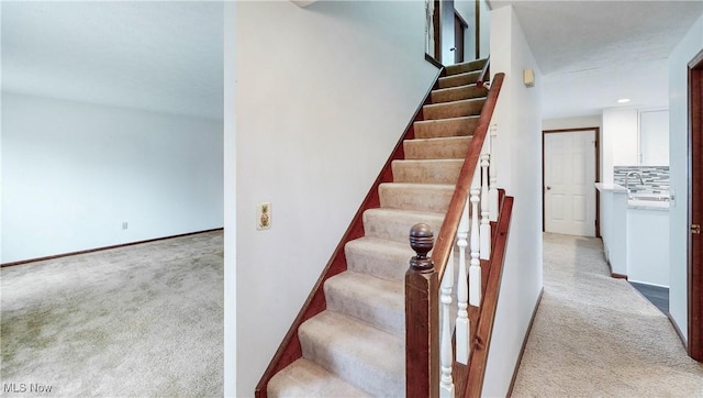 stairs featuring carpet and sink