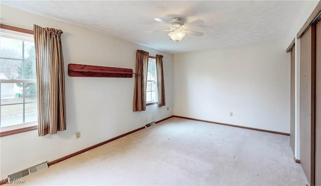 unfurnished bedroom with a closet, ceiling fan, light carpet, and a textured ceiling