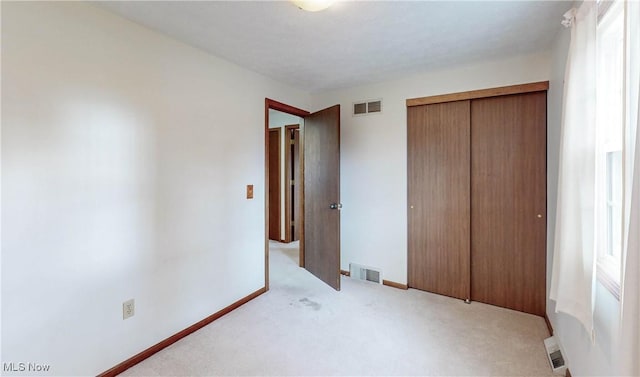 unfurnished bedroom with light colored carpet and a closet