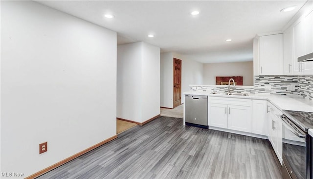 kitchen with tasteful backsplash, white cabinetry, sink, light hardwood / wood-style floors, and stainless steel appliances