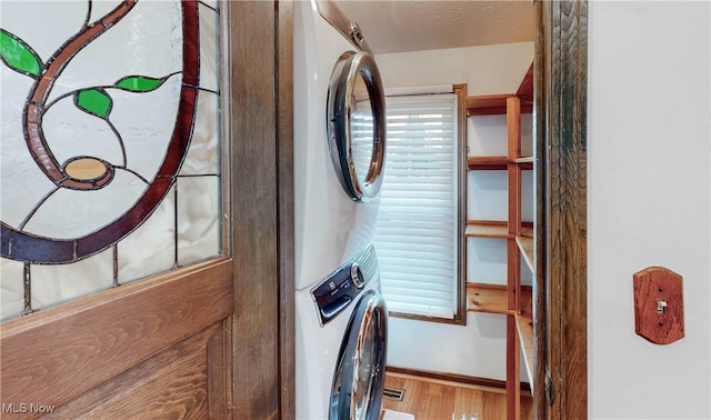 washroom featuring stacked washer / dryer, hardwood / wood-style floors, and a textured ceiling