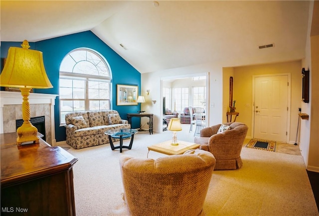 living room featuring a tiled fireplace, lofted ceiling, and light colored carpet