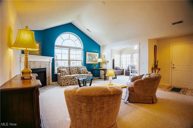 living room with a tile fireplace, lofted ceiling, a healthy amount of sunlight, and light carpet