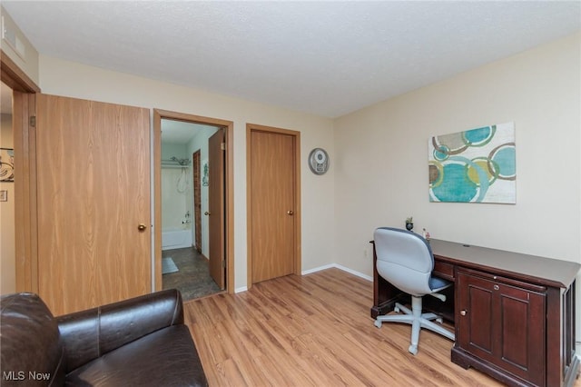 home office with light hardwood / wood-style floors and a textured ceiling