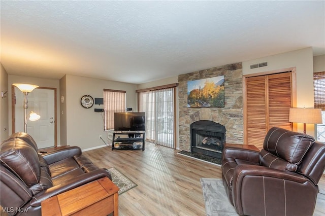 living room with a fireplace, a textured ceiling, and light wood-type flooring