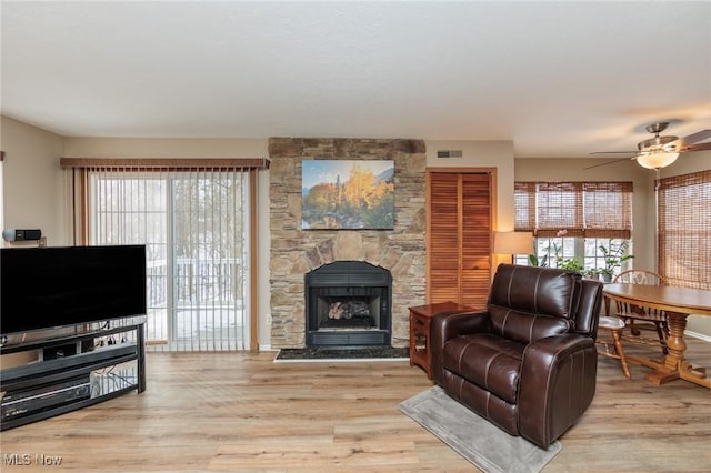 living room with ceiling fan, a wealth of natural light, a fireplace, and light hardwood / wood-style floors