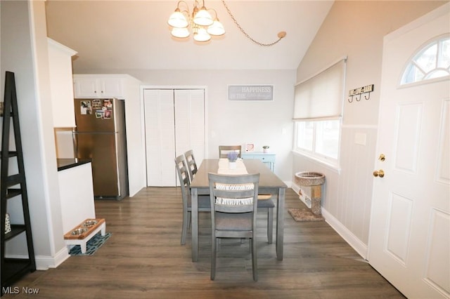 dining space with lofted ceiling, dark wood-type flooring, and an inviting chandelier