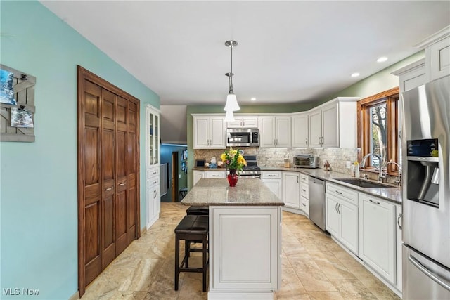 kitchen featuring pendant lighting, sink, dark stone countertops, a center island, and stainless steel appliances