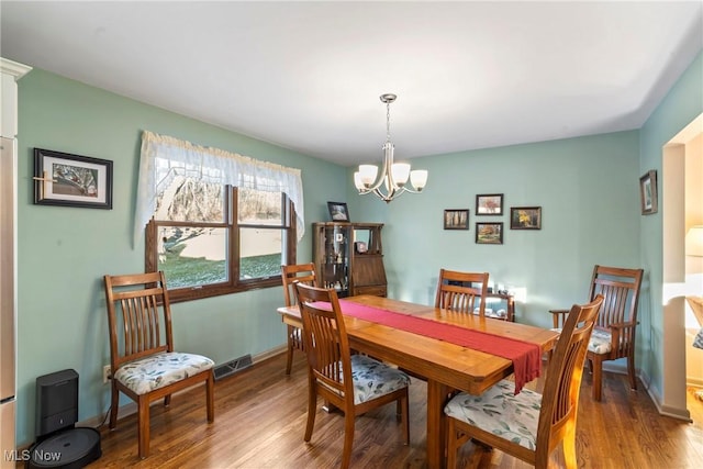 dining area with hardwood / wood-style floors and a chandelier