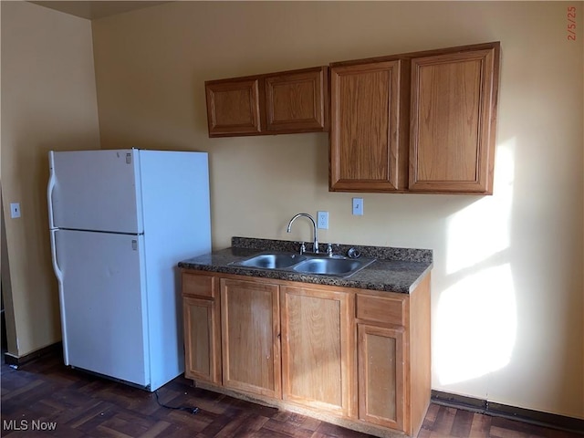 kitchen with white refrigerator, sink, and dark parquet floors