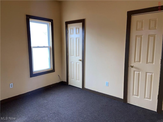 unfurnished bedroom with dark colored carpet