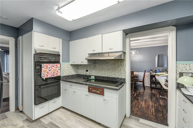 kitchen with dark stone counters, black appliances, light hardwood / wood-style floors, and white cabinets