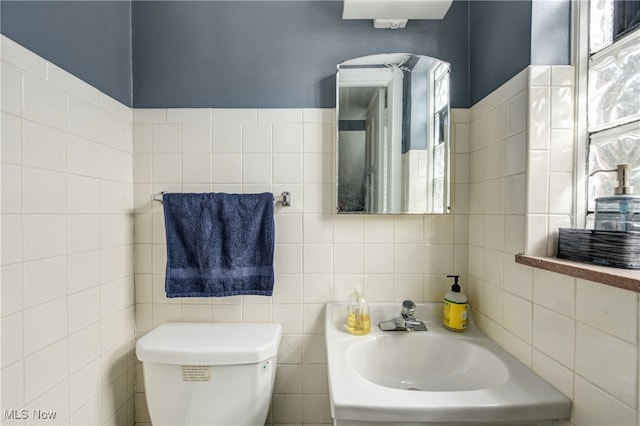 bathroom with sink, tile walls, and toilet