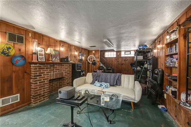 living room featuring a brick fireplace, a textured ceiling, and wood walls