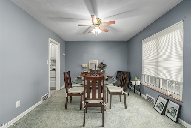 dining room with ceiling fan and light carpet