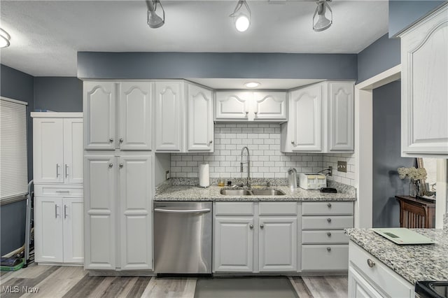 kitchen with white cabinetry, stainless steel dishwasher, sink, and light stone counters