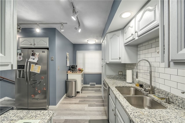 kitchen with sink, light hardwood / wood-style flooring, appliances with stainless steel finishes, white cabinetry, and light stone counters