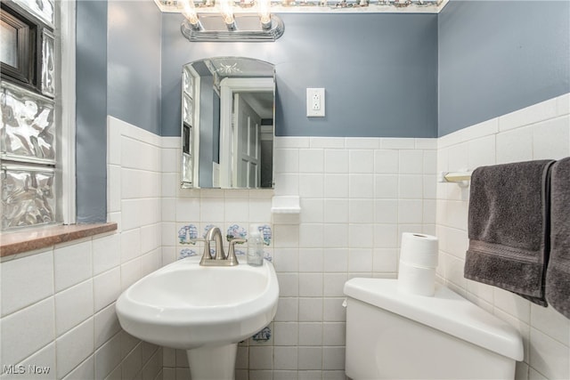 bathroom with sink, tile walls, and toilet