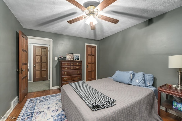 bedroom with a textured ceiling, dark hardwood / wood-style floors, and ceiling fan