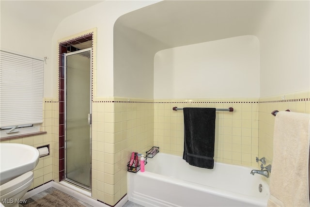 bathroom featuring tile walls, shower with separate bathtub, and toilet