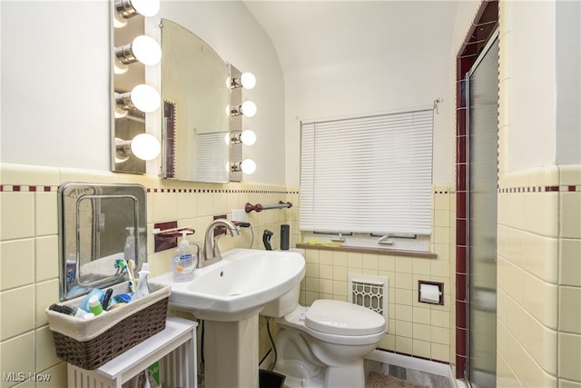 bathroom featuring toilet, sink, and tile walls