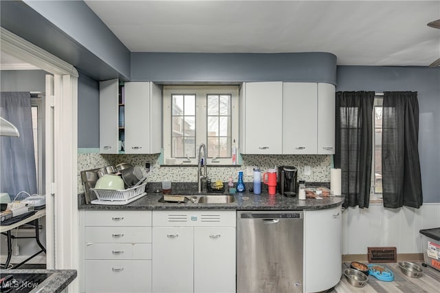 kitchen featuring dishwasher, sink, dark stone countertops, and white cabinets