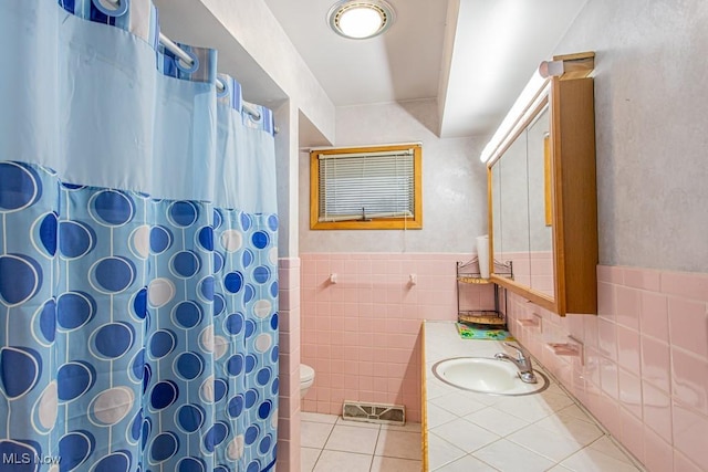 bathroom featuring curtained shower, sink, tile walls, tile patterned flooring, and toilet