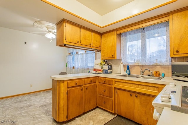 kitchen featuring ceiling fan, kitchen peninsula, sink, and decorative backsplash