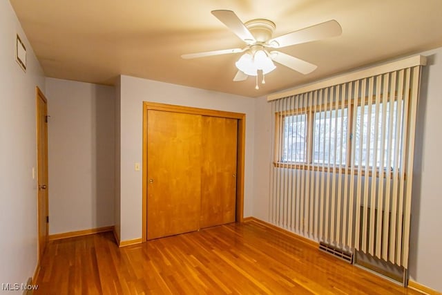 unfurnished bedroom featuring wood-type flooring, ceiling fan, and a closet