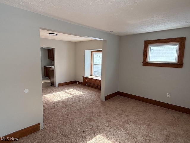 empty room with light colored carpet and a textured ceiling