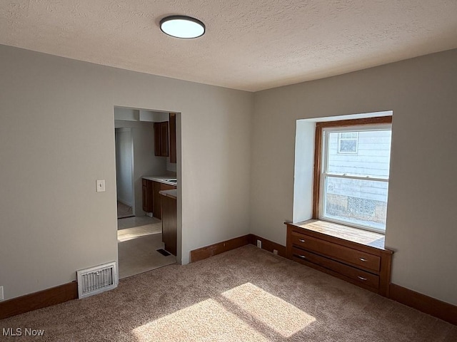 carpeted spare room with a textured ceiling