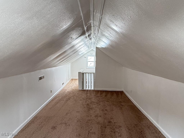 bonus room featuring vaulted ceiling, carpet, and a textured ceiling