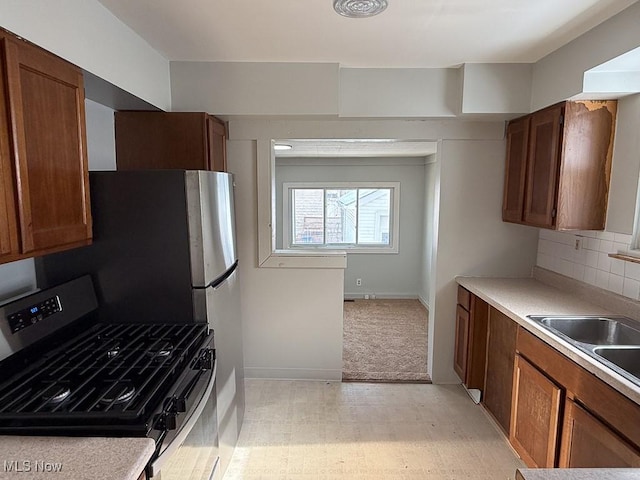 kitchen with stainless steel range with gas stovetop, sink, and decorative backsplash