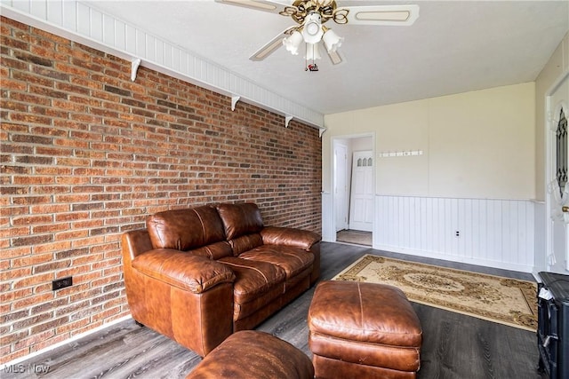 living room with hardwood / wood-style flooring, ceiling fan, and brick wall