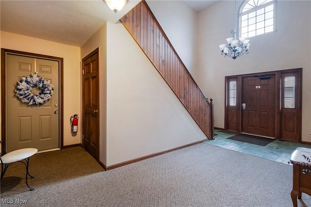 foyer entrance with a notable chandelier, a towering ceiling, light colored carpet, and a textured ceiling