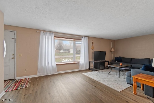 living area featuring a textured ceiling, baseboards, and wood finished floors