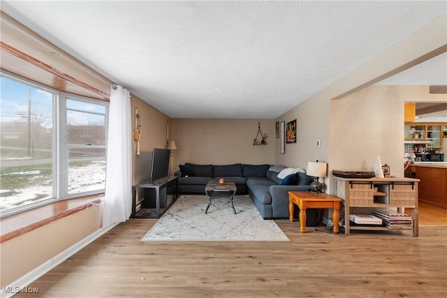 living area with light wood-style floors, baseboards, and a textured ceiling