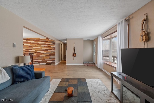 living area featuring light wood finished floors, baseboards, and a textured ceiling